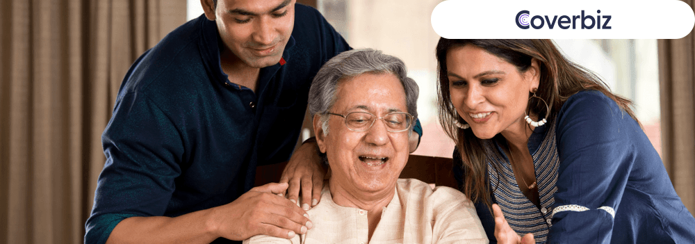 An elderly Indian man with a man and a woman looking at a piece of paper, they all seem happy and smiling
